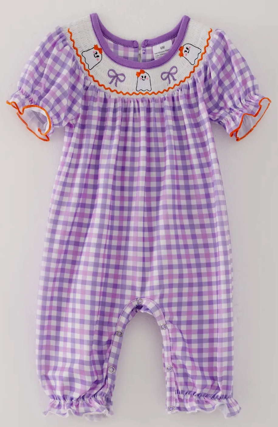 Purple checkered baby romper with decorative elements on a light gray background